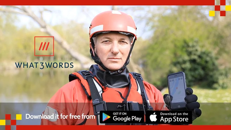 A person wearing a red helmet and lifejacket holding a smartphone with the What3words logo beside them. Text at the bottom encourages downloading the app from Google Play or the App Store.