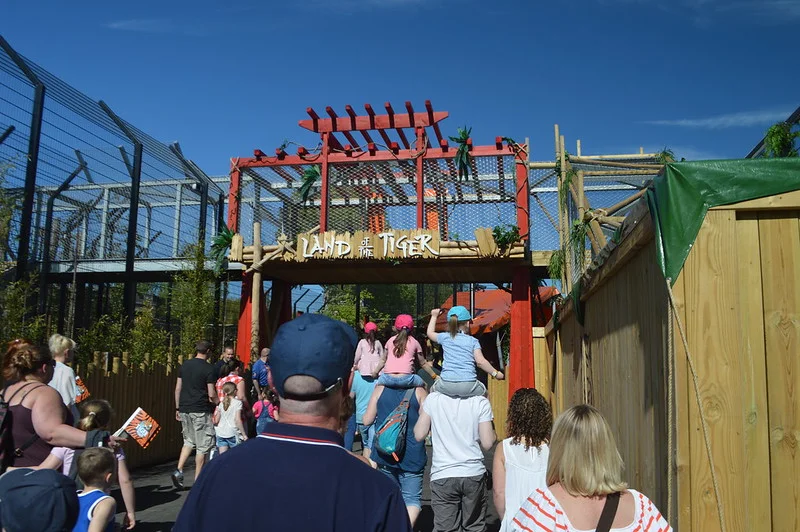 People walking towards the "Land of the Tiger" entrance at a zoo.