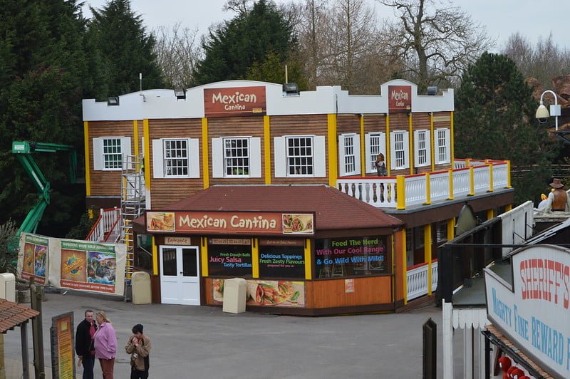 Chessington World of Adventures Resort 2 A two-story Mexican Cantina restaurant with wooden exterior, large signage, and outdoor seating area on the upper floor.