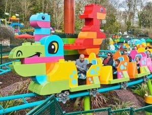 People enjoying a ride on a colourful toy-themed roller coaster ride at a theme park.