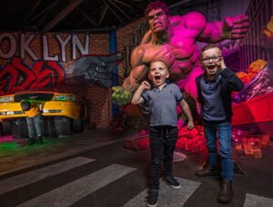 Madame Tussauds Blackpool 1 Two children pose enthusiastically in front of a large statue of the Hulk in a themed environment, with graffiti and a yellow car in the background.