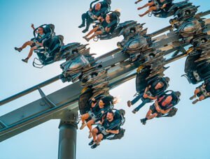 THORPE PARK Resort 1 People riding a flying roller coaster with inverted seats and excitement on their faces.