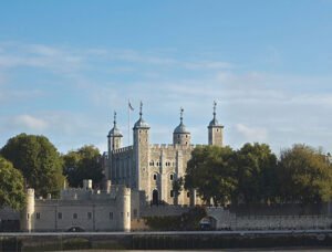 Tower of London surrounded by trees, viewed from across the River Thames.